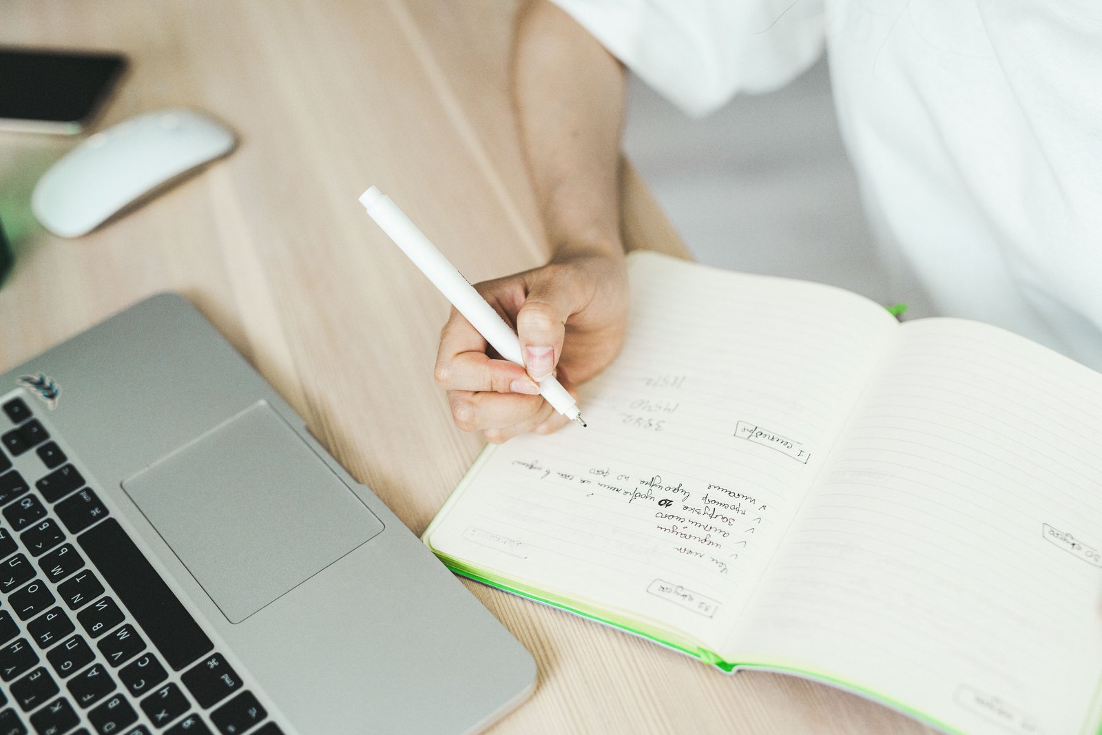 Writer planning content ideas in a notebook beside a laptop