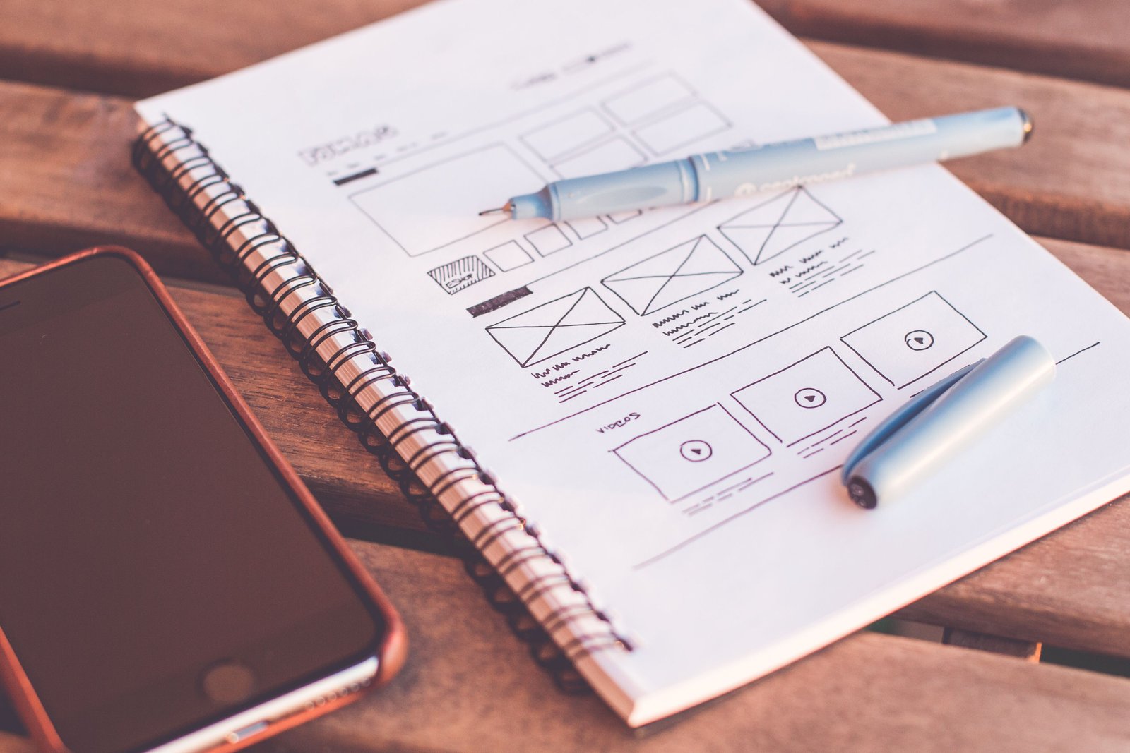 Notebook with website wireframes beside a smartphone
